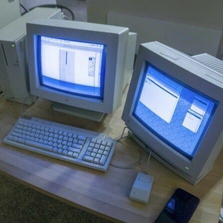 two computer monitors sitting on top of a wooden desk next to a keyboard and mouse