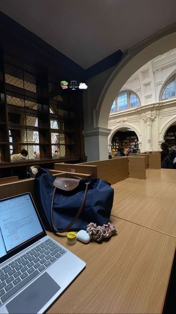 an open laptop computer sitting on top of a wooden table next to a bag and other items