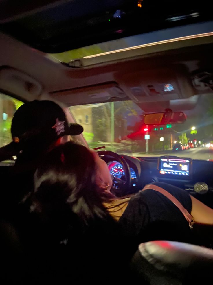 two people sitting in the back seat of a car at night with their head up