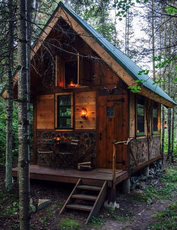 a small cabin in the woods with stairs leading up to it's front door