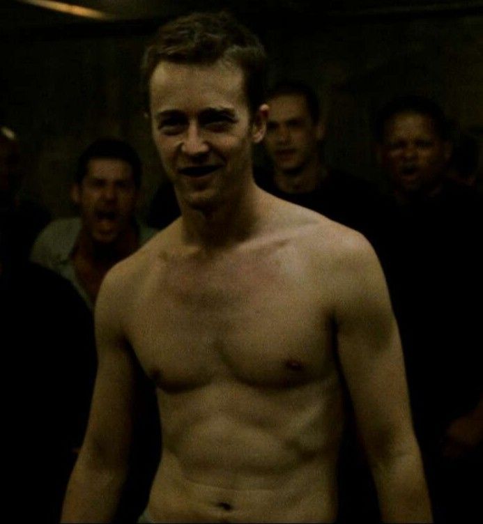 a shirtless man standing in front of other men