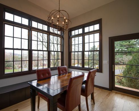 the dining room table is surrounded by brown leather chairs, and there are three large windows