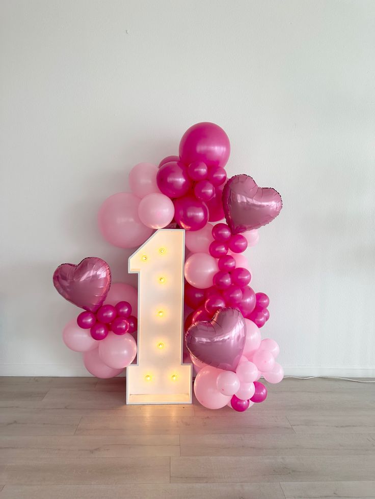 the number one balloon is surrounded by pink and white balloons in the shape of hearts