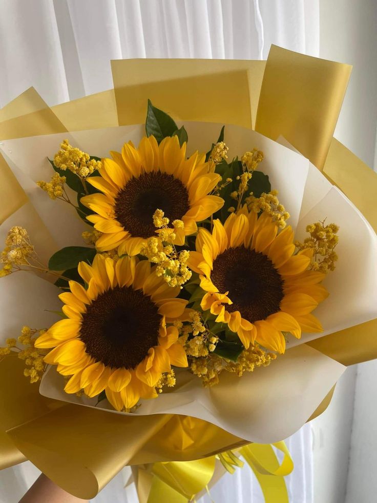 a bouquet of sunflowers is wrapped in yellow ribbon