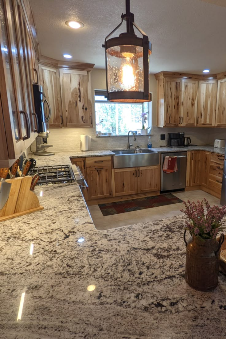 a kitchen with granite counter tops and wooden cabinets, an island in the middle has a potted plant on it