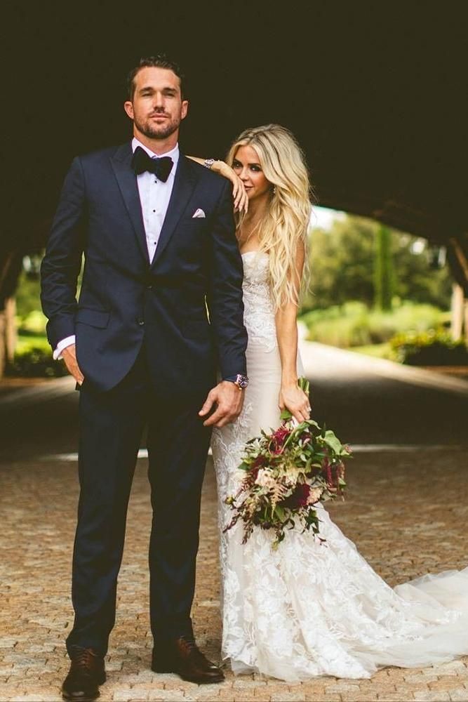 a bride and groom posing for a photo in front of a covered walkway at their wedding