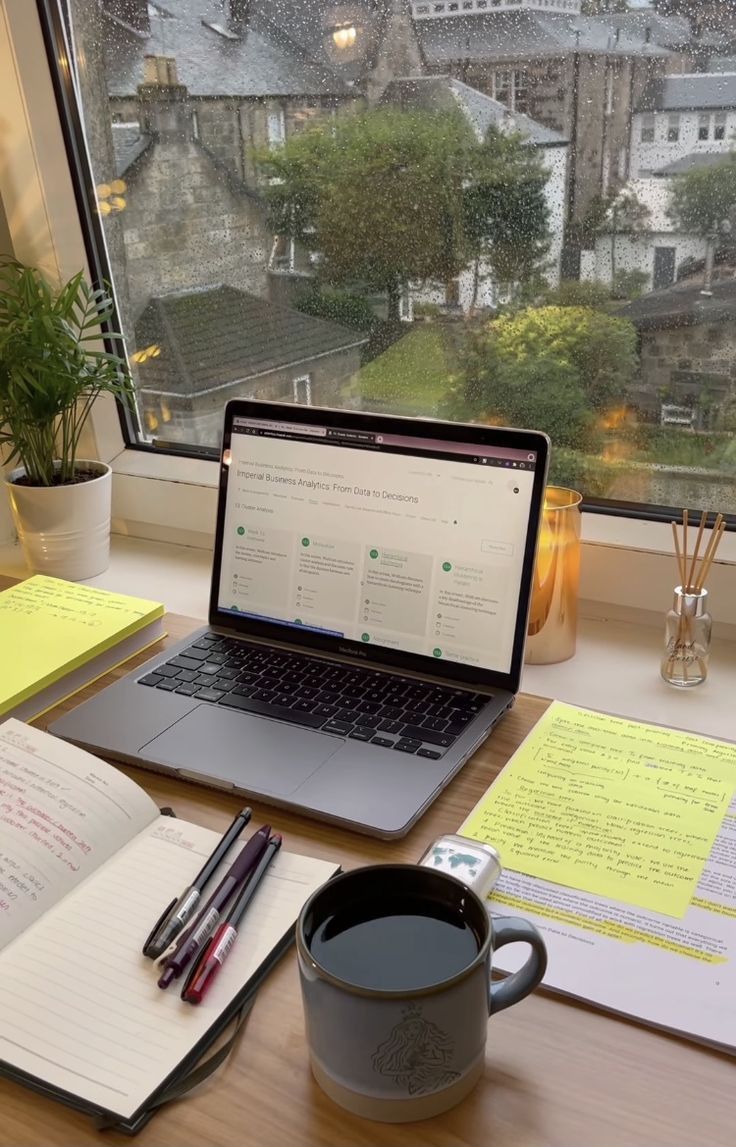 an open laptop computer sitting on top of a desk next to a cup of coffee