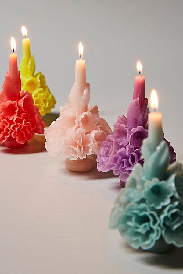 five candles with different colored flowers on them