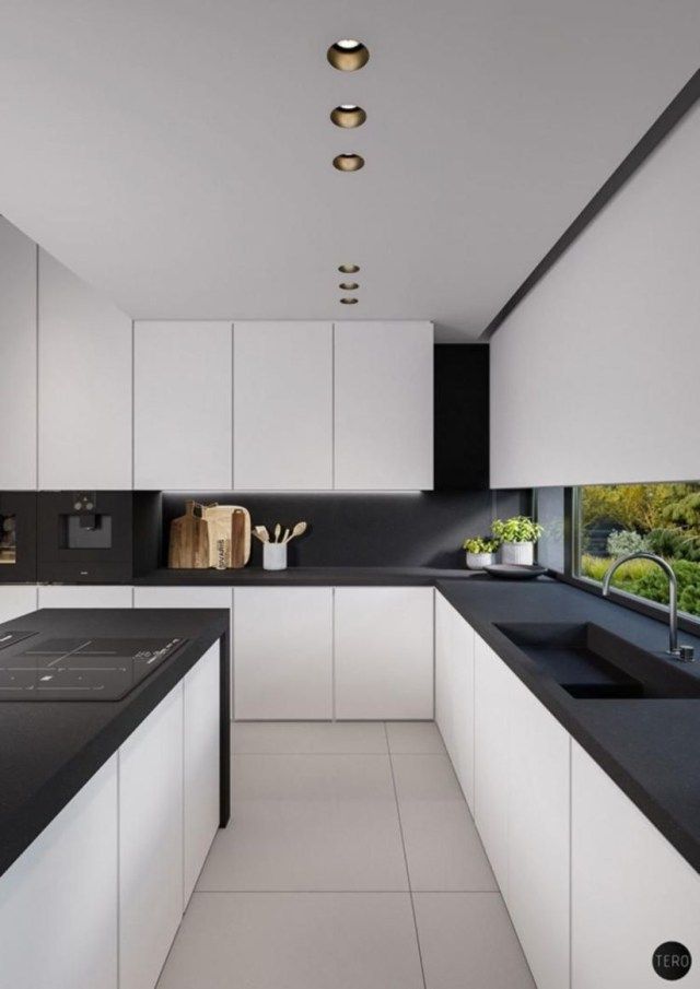 a modern kitchen with black counter tops and white cabinetry, along with an island