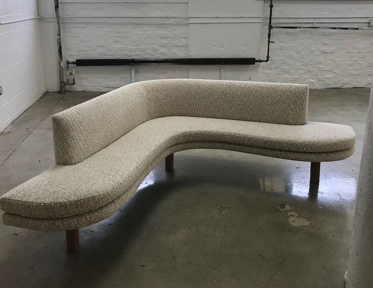 a curved bench sitting in the middle of a room with white paint on the walls