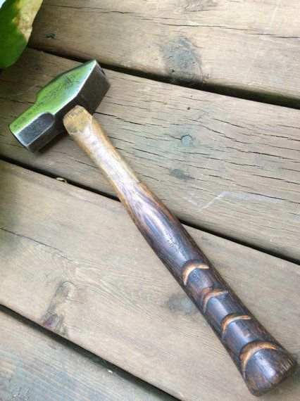 a hammer and pickle sitting on top of a wooden table next to a potted plant