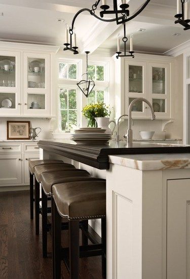 a kitchen with white cabinets and black counter tops on a wooden floor next to an island