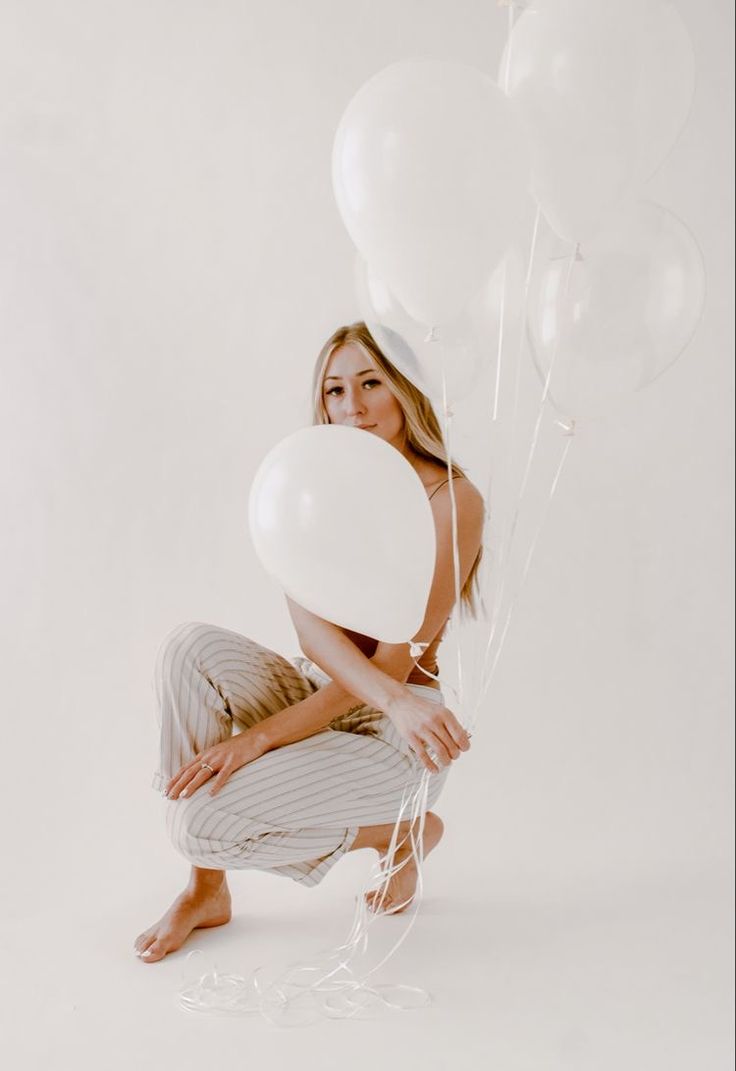 a woman kneeling down with balloons in front of her