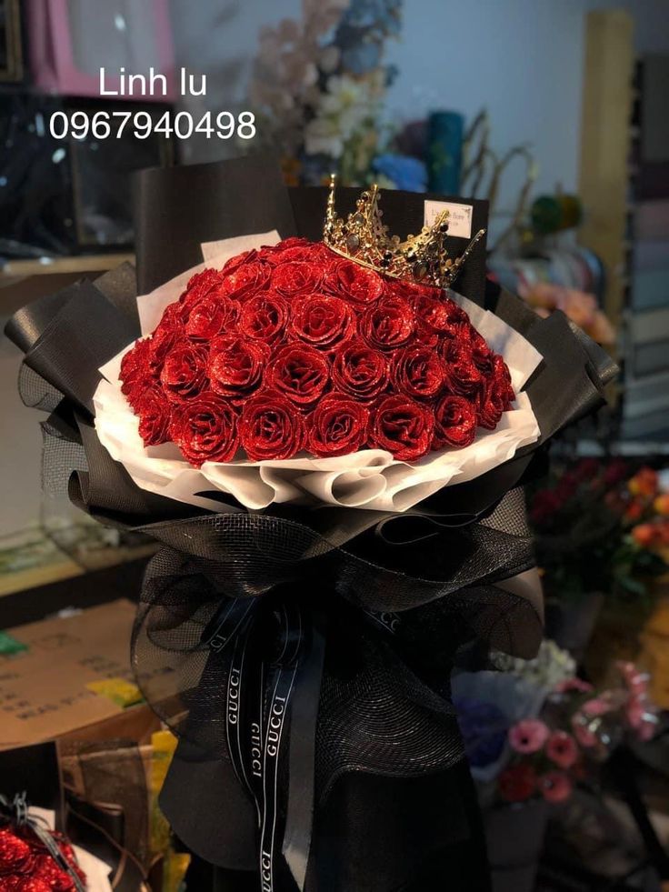 a bouquet of red roses with a crown on top is sitting in front of a table