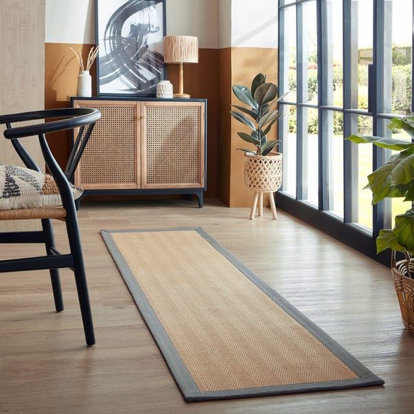 a living room with a rug and chair in front of a large glass door that leads to the outside