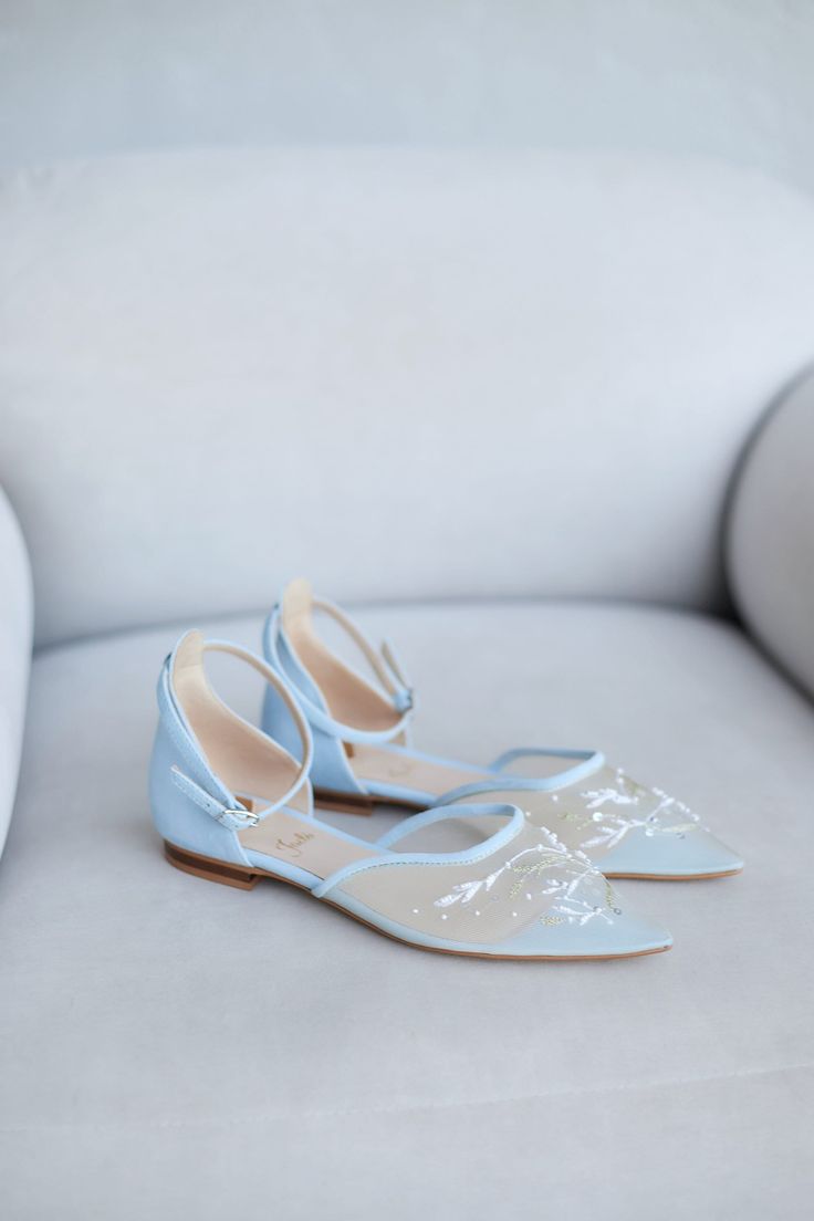 a pair of blue and white shoes sitting on top of a white couch next to a pillow