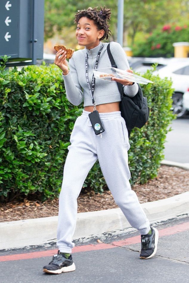 a woman walking down the street while holding a donut in one hand and a sandwich in the other