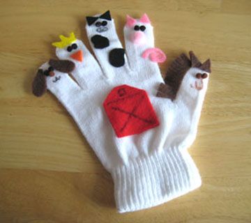 a pair of white gloves with cats on them sitting on top of a wooden table