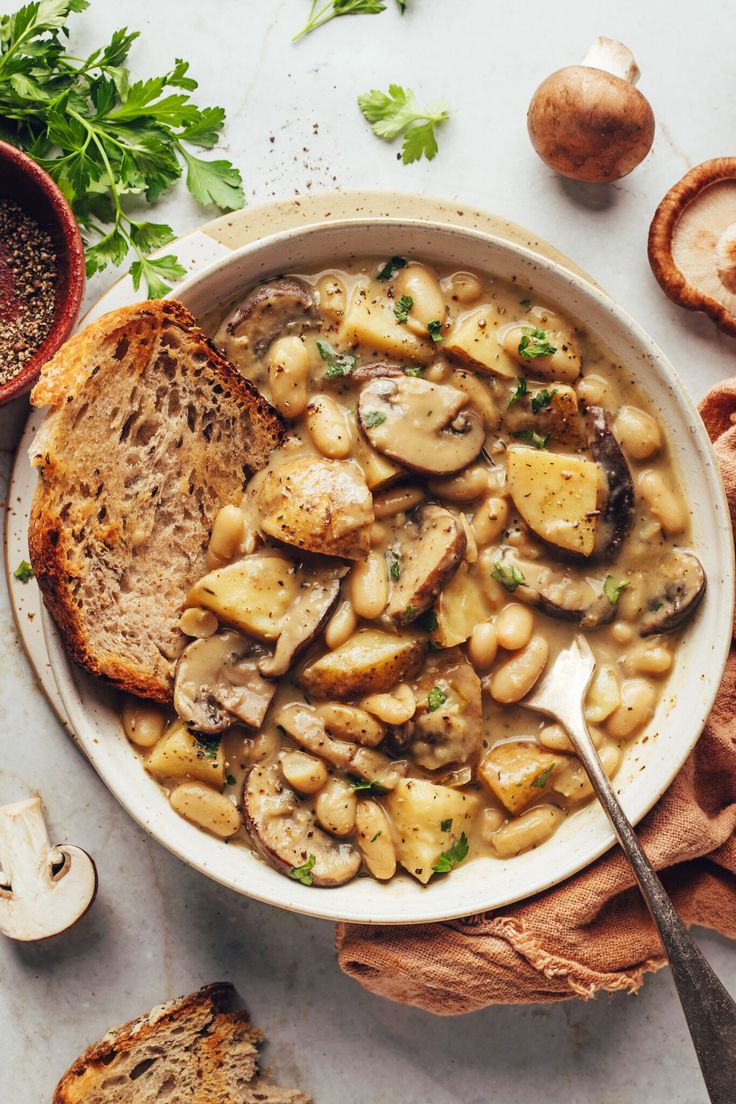 a white bowl filled with mushroom soup next to bread