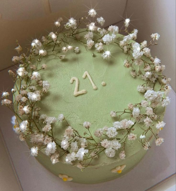 a green cake with white flowers and the number twenty on it