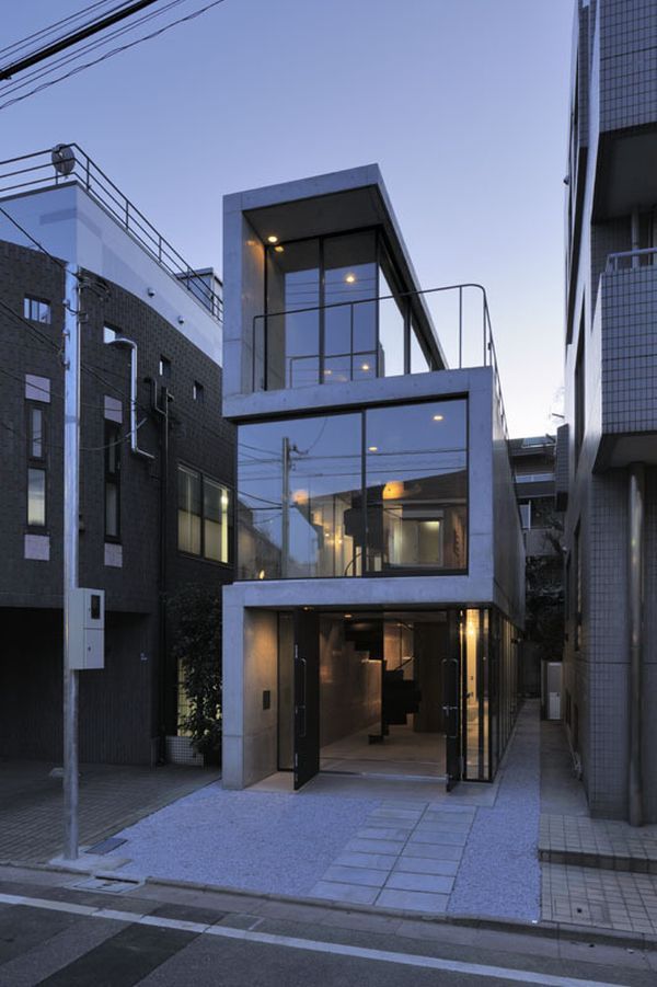 an apartment building with glass windows and balconies on the top floor is lit up at night