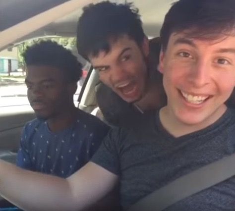 three young men are sitting in the back seat of a car and one is smiling