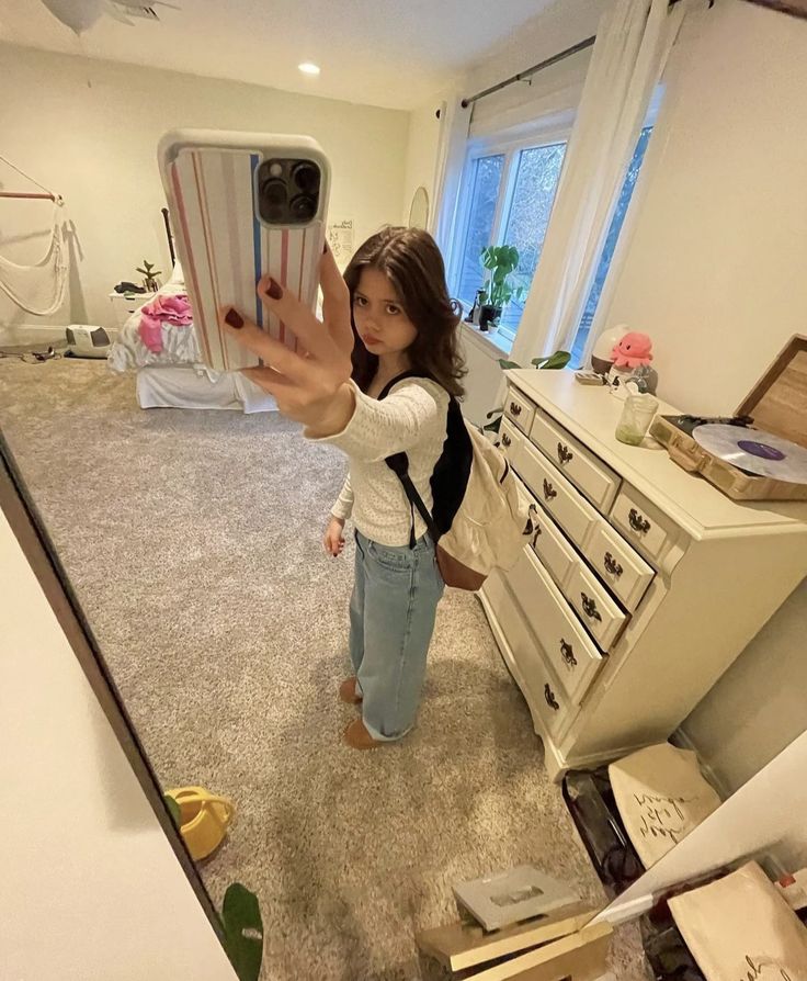 a woman taking a selfie with her cell phone in the living room while holding it up