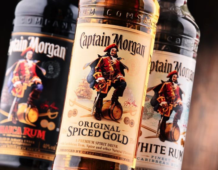 three bottles of captain morgan's spiced gold rum on a wooden table top