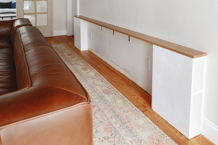 a brown leather couch sitting next to a wooden shelf