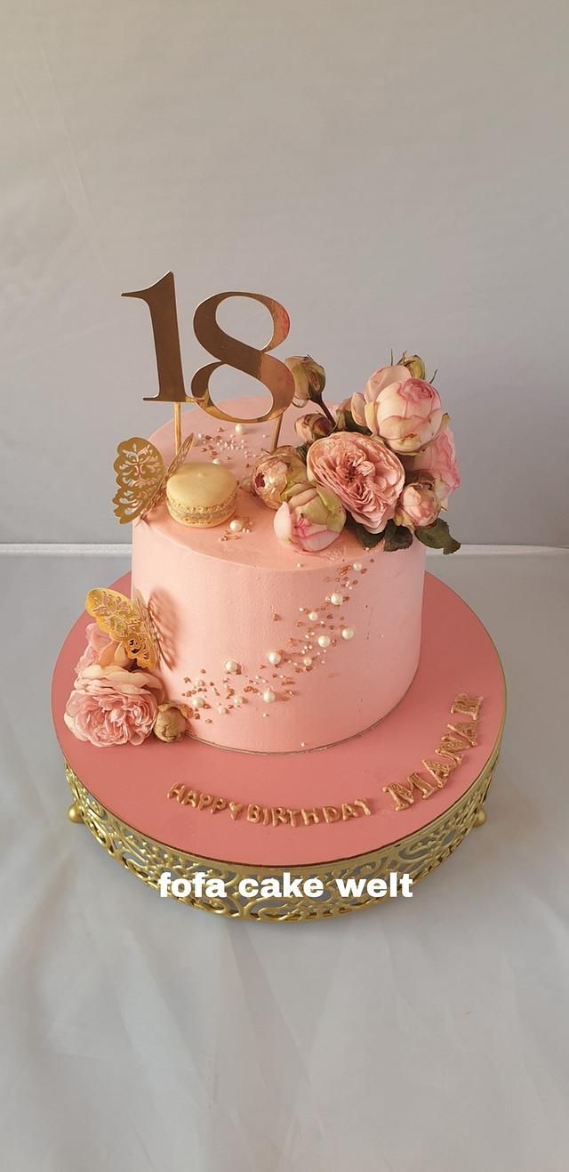 a pink cake with gold numbers and flowers on top