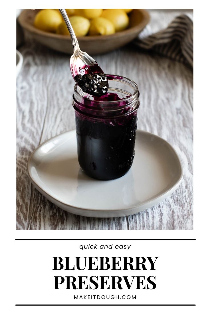 blueberry preserves in a glass jar with a spoon on the plate next to it