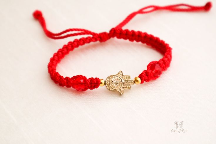 The Fatima Hand Charm Bracelet is a perfect gift for the loved one in your life. It's made from a high quality woven thread that can stretch to fit most any wrist size, showcasing a gold Hamsa hand against a crimson backdrop. Hamsa, meaning "five" in Arabic, is a symbol of protection, luck, and sometimes specifically the "hand of God." Wear the Hamsa hand to keep you in good health and ward off the evil eye. Use it to give as a great gift for someone you care about to let them know you're always Gold Hand-strung Friendship Bracelets As Gift, Gold Hand Wrapped Friendship Bracelets As Gift, Gold Spiritual Braided Bracelet For Good Luck, Adjustable Gold Spiritual Stretch Bracelet, Adjustable Spiritual Gold Stretch Bracelet, Spiritual Red Stretch Bracelet As Gift, Adjustable Red Bracelet For Blessing, Spiritual Red Stretch Bracelet Gift, Gold Braided Bracelet For Good Luck