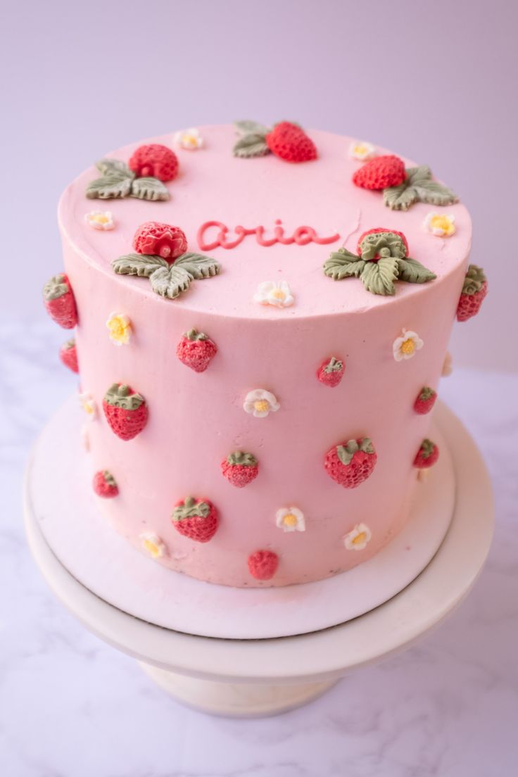 a pink cake decorated with strawberries and flowers