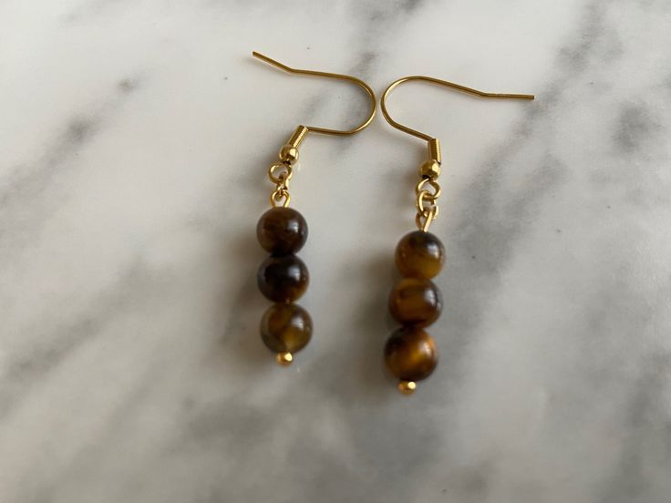 Tiger's Eye is the stone of courage, power, and protection. It bestows on us the ability to maintain our presence and power in this physical world. Tiger's Eye also protects from the evil eye and can remove negative energies. It is a stone of health and vitality. Every beads is different so every earring is unique. Made with stainless steel Spiritual Dangle Earrings For Everyday Wear, Spiritual Brown Hypoallergenic Jewelry, Brown Hypoallergenic Spiritual Jewelry, Hypoallergenic Brown Spiritual Jewelry, Hypoallergenic Spiritual Dangle Earrings, Spiritual Round Hypoallergenic Earrings, Spiritual Hypoallergenic Round Earrings, Hypoallergenic Round Spiritual Earrings, Tiger Eye Earrings