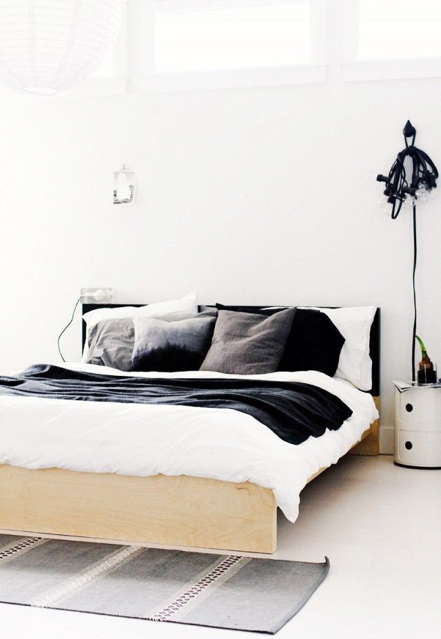 a bed sitting in the middle of a bedroom next to a white wall and floor