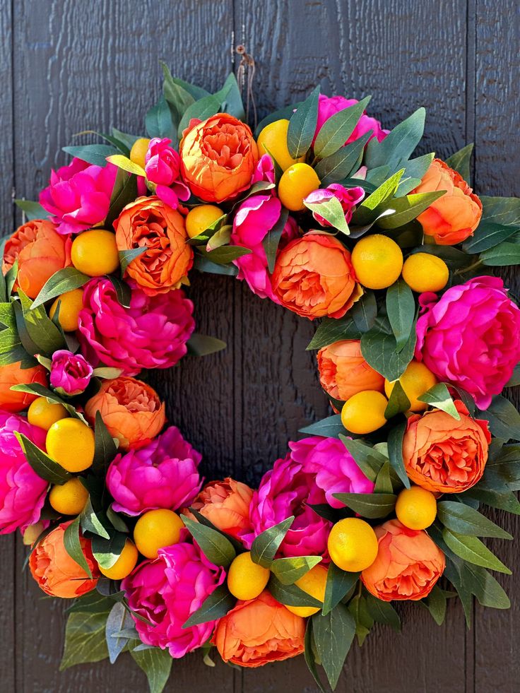 a wreath with oranges and pink flowers on it