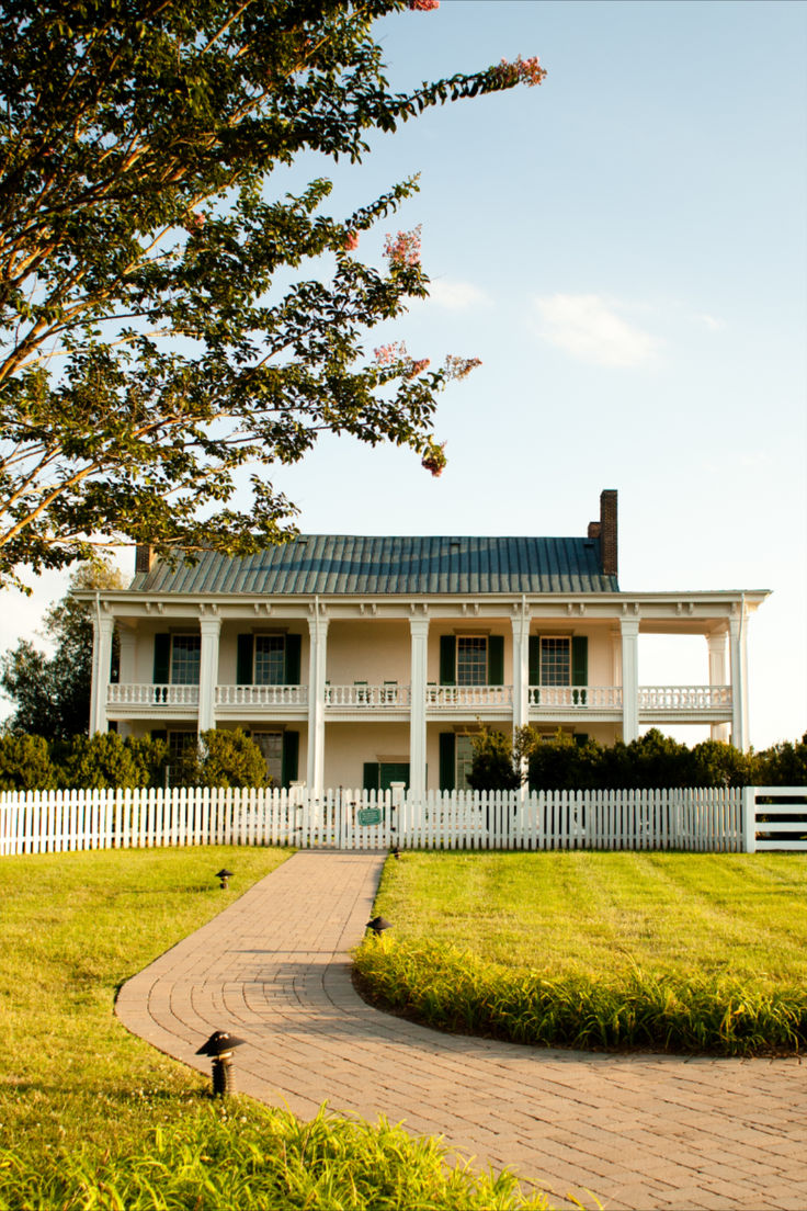 a large white house sitting on top of a lush green field