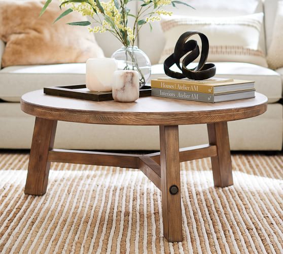 a coffee table with books and flowers on it in front of a white couch,