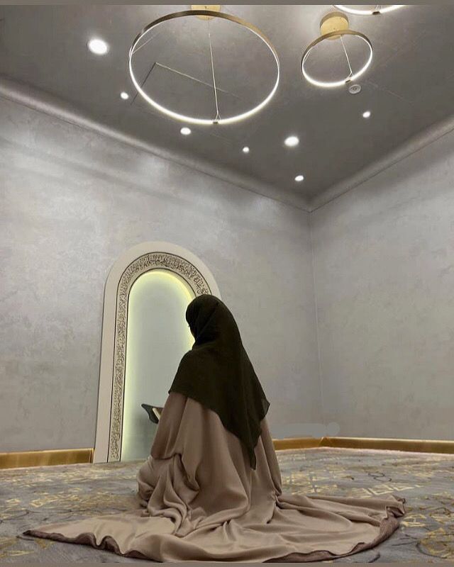 a woman sitting on top of a rug in front of a mirror wearing a veil