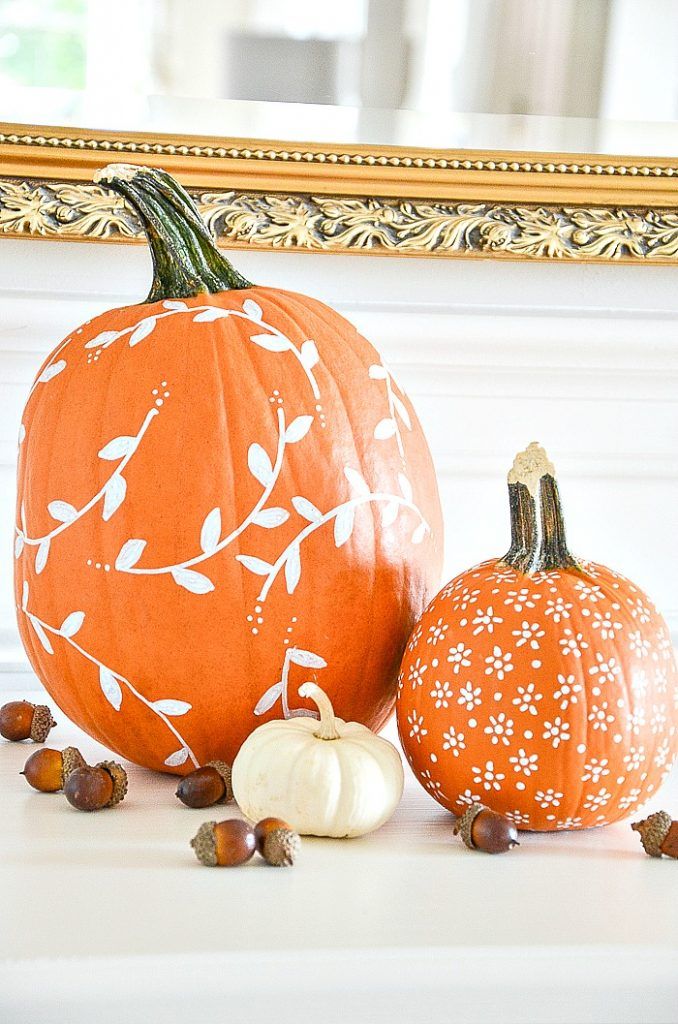 two pumpkins sitting next to each other in front of a gold framed mirror with leaves on it