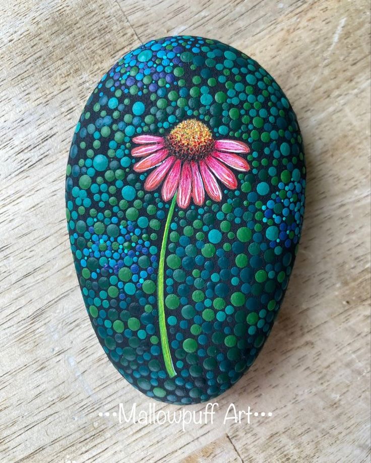 a painted rock with a pink flower on it