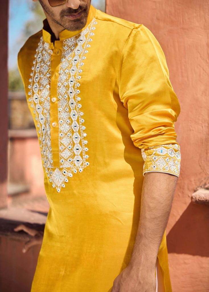 The mehrangarh kurta in mustard is a vibrant and stylish choice for Indian grooms, designed for haldi, mehndi, or sangeet ceremonies. Crafted from premium viscose cotton silk, this kurta provides a smooth and comfortable feel, ideal for festive occasions. Paired with an ivory salwar, this kurta ensemble offers a balanced and sophisticated look.The mehrangarh kurta is an excellent choice for grooms seeking a traditional yet contemporary outfit. Pair with traditional or modern footwear for a polished appearance at pre-wedding events. Indian Groom, Bespoke Tailoring, Contemporary Outfits, Cotton Silk, Pre Wedding, Wedding Events, Mustard, Festival, Silk