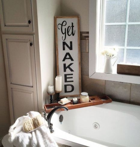 a bathroom with a bathtub, candles and a sign that says get naked on it