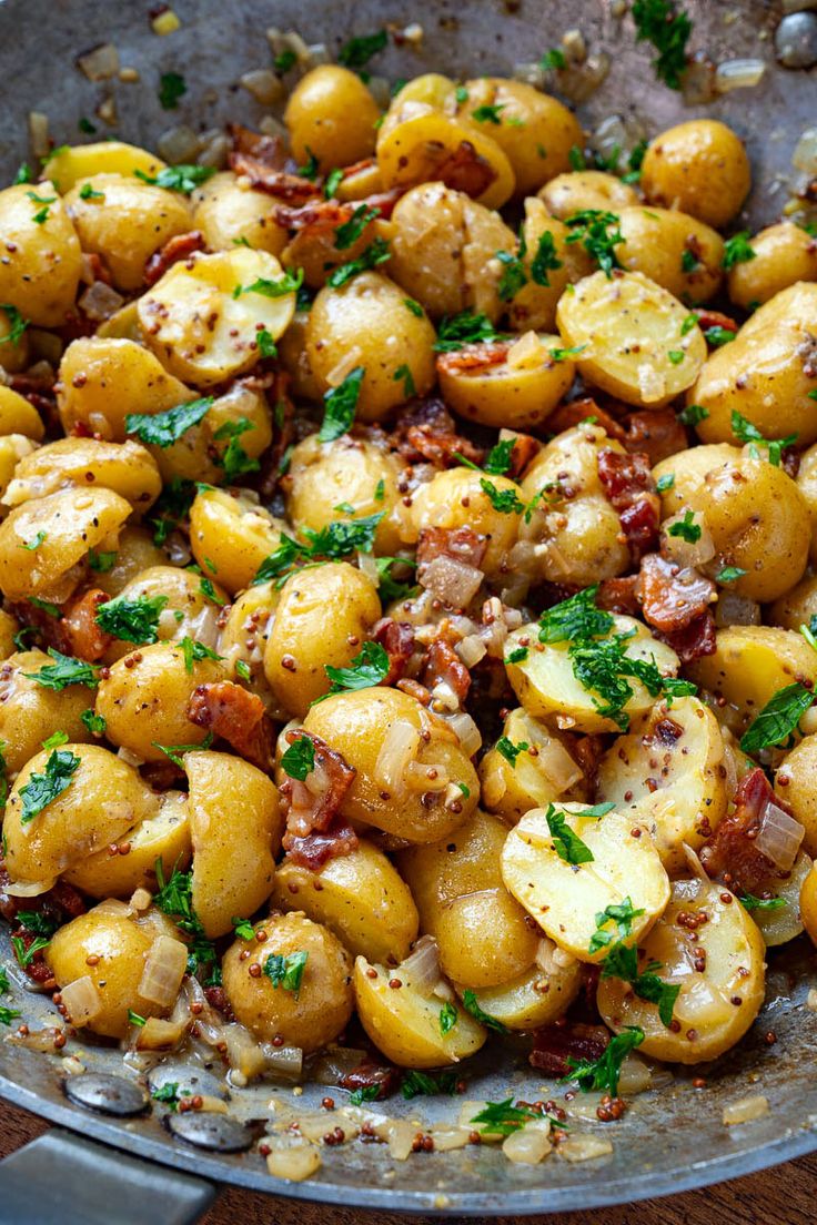 potatoes with bacon and parsley in a frying pan on a wooden table top