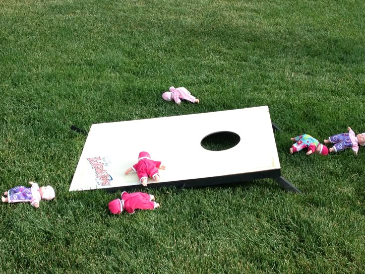 several stuffed animals laying on top of a white board in the middle of some grass