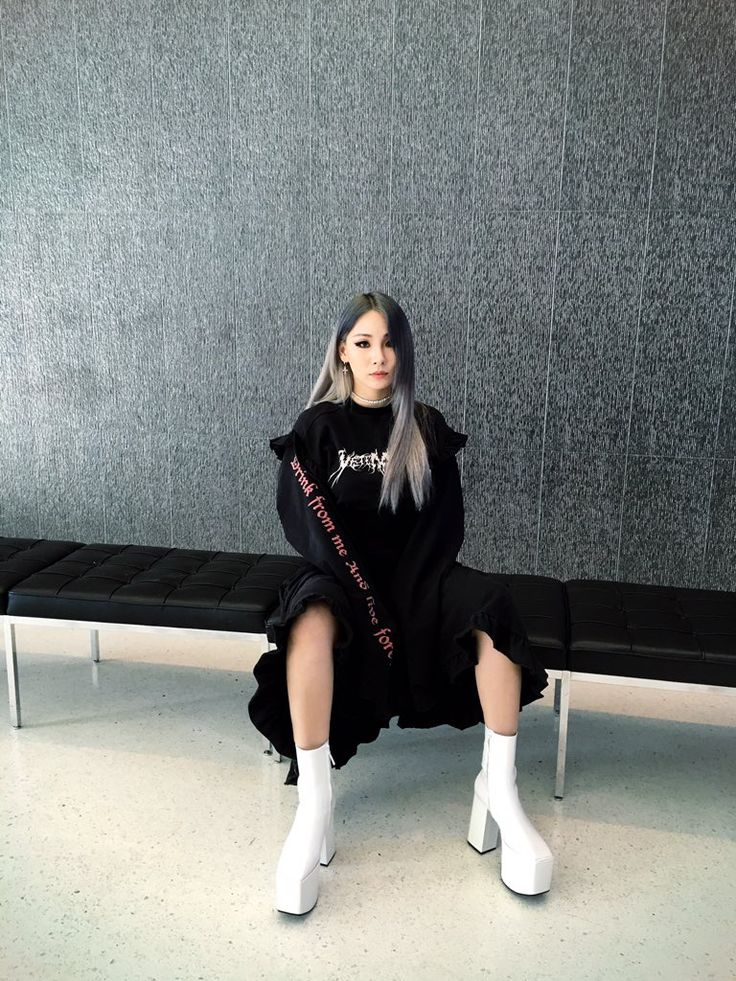 a woman sitting on a bench wearing white boots and a black shirt with the word love written on it