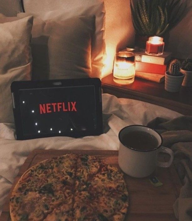 a pizza sitting on top of a wooden cutting board next to a cup of coffee