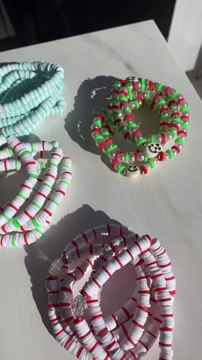 three bracelets sitting on top of a white table next to each other and one has candy canes in it