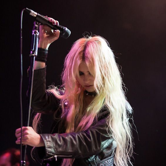 a woman with long blonde hair holding a microphone in her hand and singing on stage