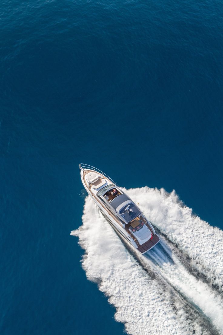 an aerial view of a motor boat speeding through the blue water in front of another boat